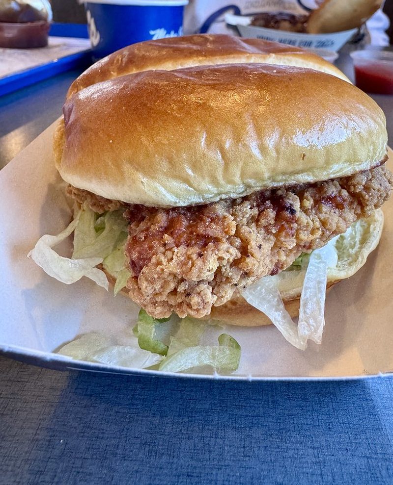 A fried chicken burger with lettuce in a brioche bun on a paper tray